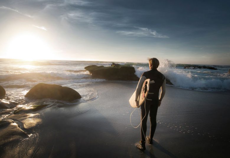 Man with surfboard looks at the ocean