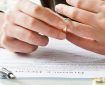 Man takes wedding ring off finger while reading divorce papers