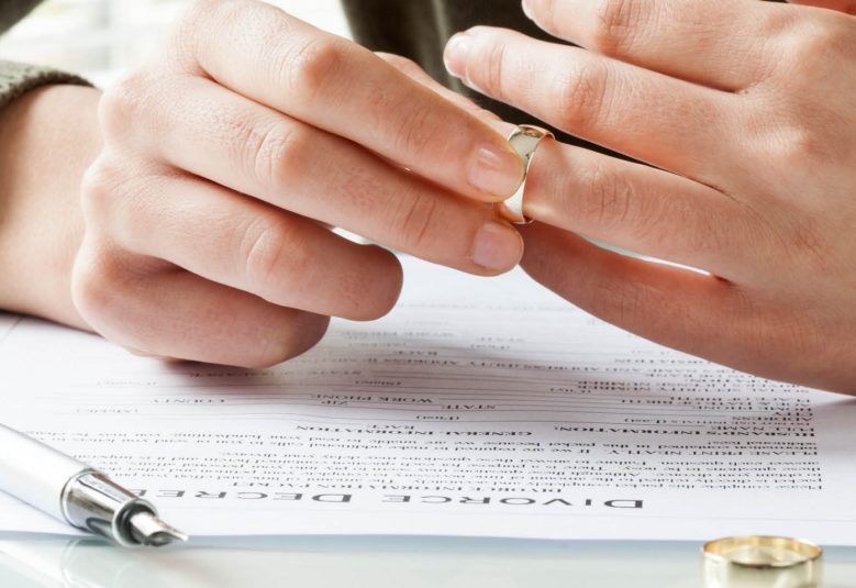 Man takes wedding ring off finger while reading divorce papers
