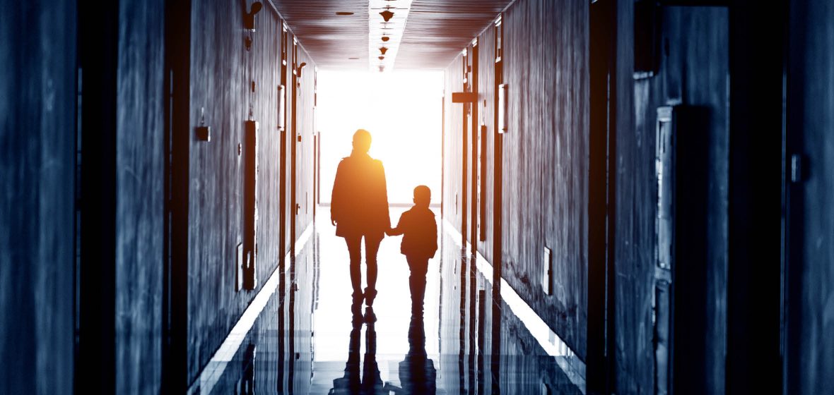 Silhouette of adult and child walking down a hallway