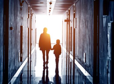 Silhouette of adult and child walking down a hallway