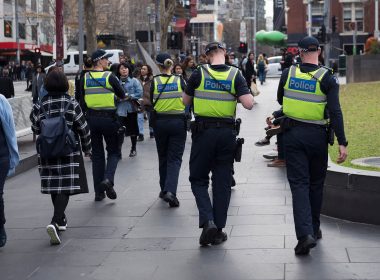 Four police walking down a street among pedestrians