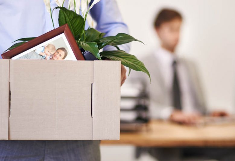 man carries box of personal items across an office