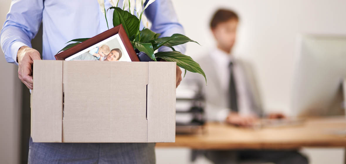 man carries box of personal items across an office