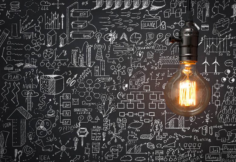 One light bulb shining on a chalkboard with sketches