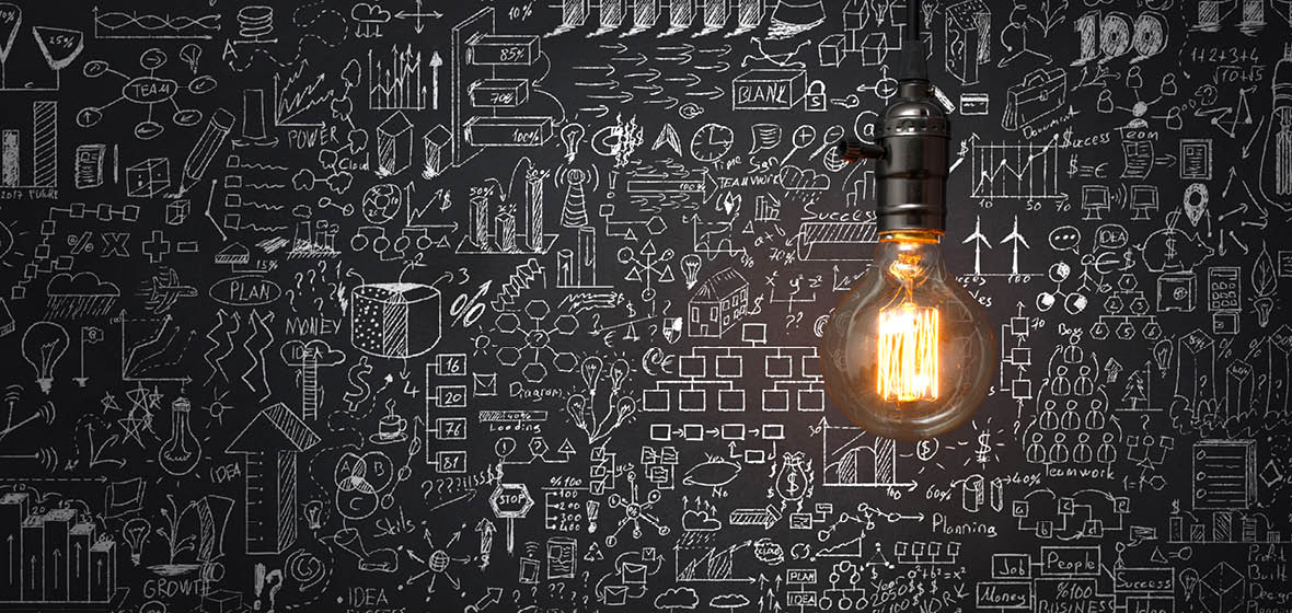 One light bulb shining on a chalkboard with sketches