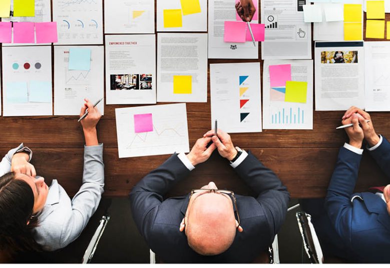 three solicitors at a desk reading documents covered with post-it notes