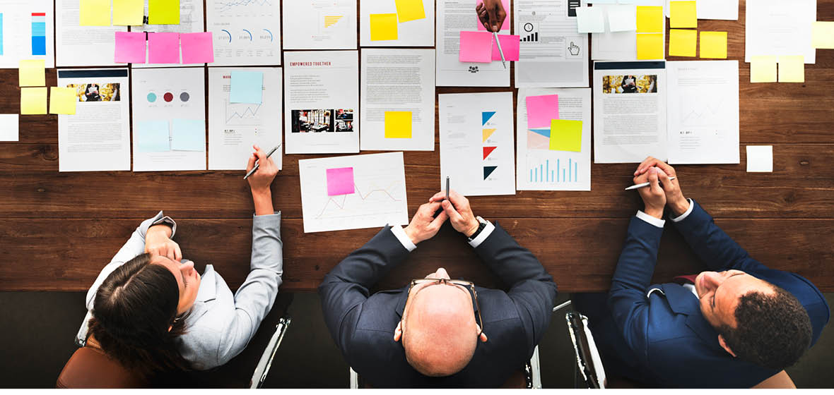 three solicitors at a desk reading documents covered with post-it notes