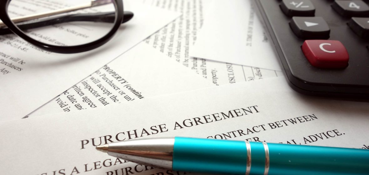 Close up of purchase agreement with a pen, calculator and spectacles