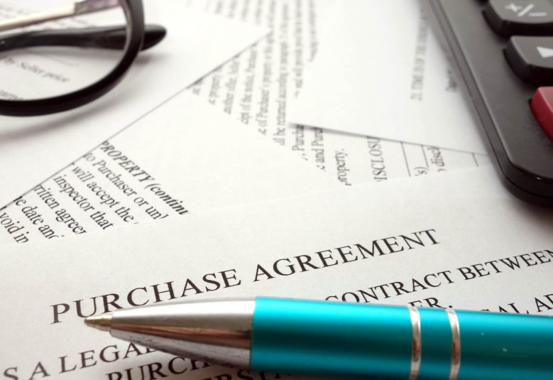 Close up of purchase agreement with a pen, calculator and spectacles