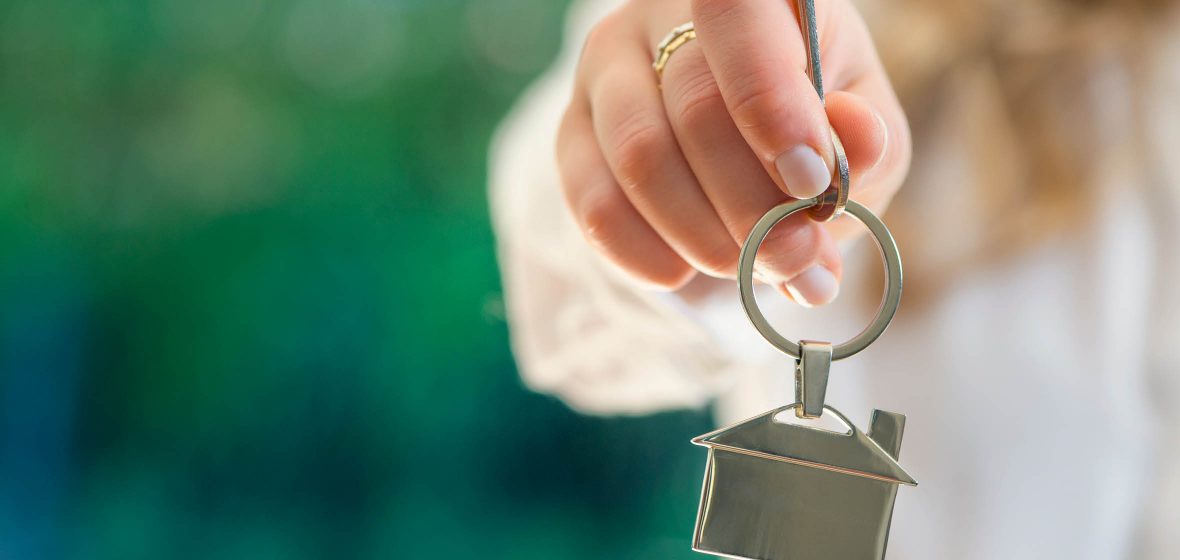 Woman's holding key chain in the shape of a house