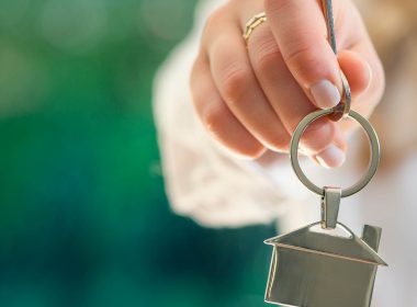 Woman's holding key chain in the shape of a house