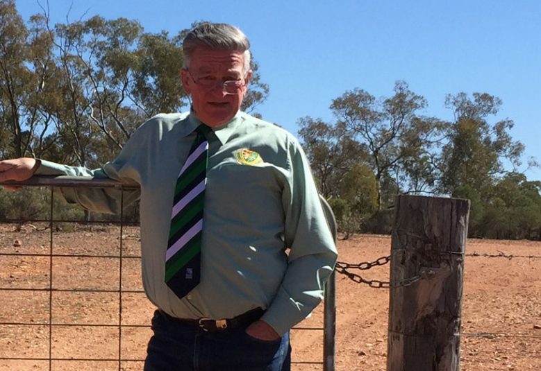 Cobar solicitor and conveyancer Peter Payne standing in front of a barbed wired fence in regional NSW.
