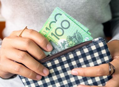 Woman putting Australian bank notes into wallet.