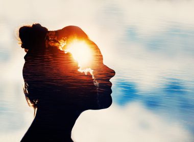 Silhouette of young woman on sky background with sun in her head.