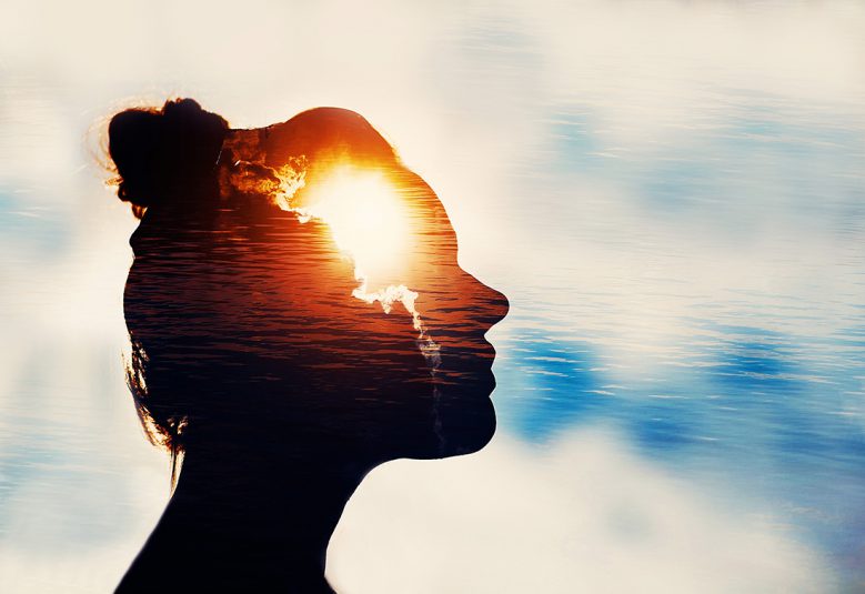 Silhouette of young woman on sky background with sun in her head.