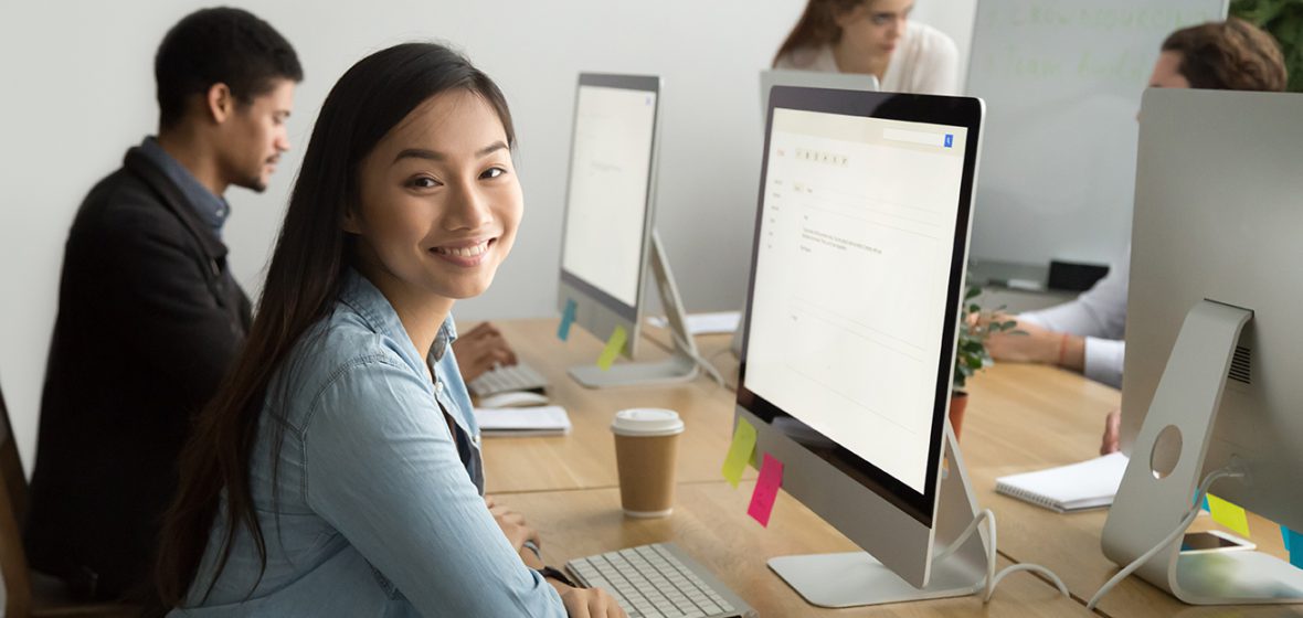 Young employee, sitting at her computer smiling