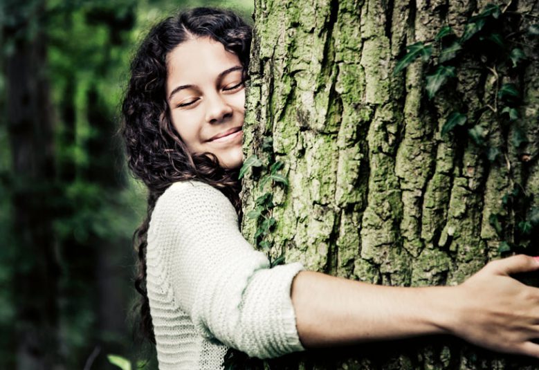 Woman hugs the trunk of a tree.