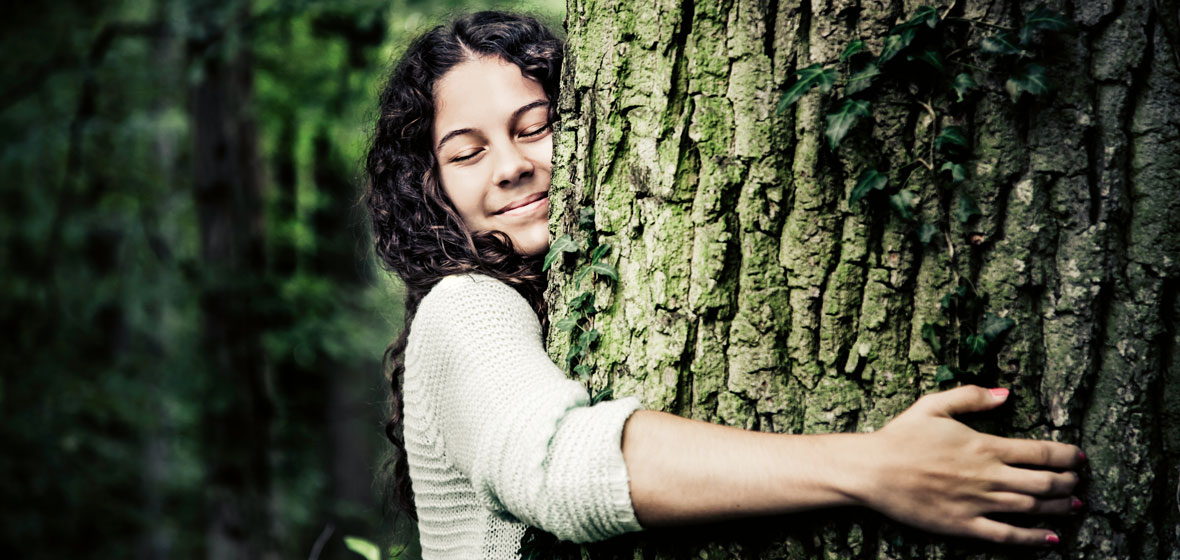 Woman hugs the trunk of a tree.
