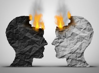 Two paper-mache black and white human heads facing each other with flames and smoke