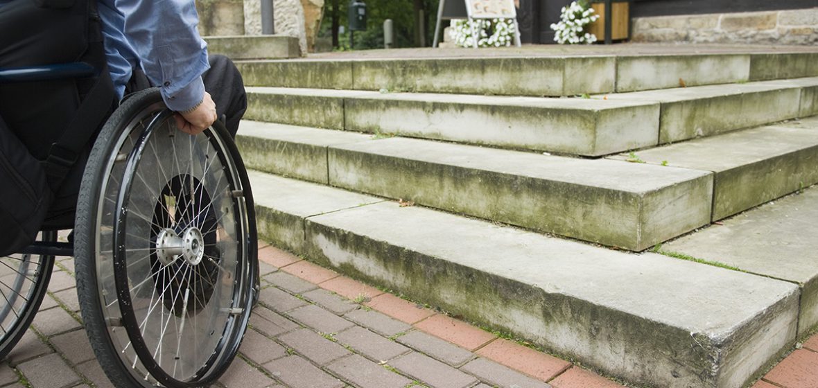Wheelchair user in front of staircase barrier