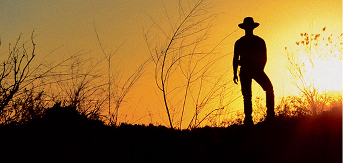 Silhouette of a farmer in a field at sunrise