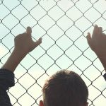 child holding onto wire fence