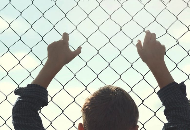 child holding onto wire fence