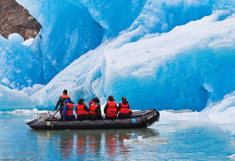 group of people in boat looking at waterfall in Alaska