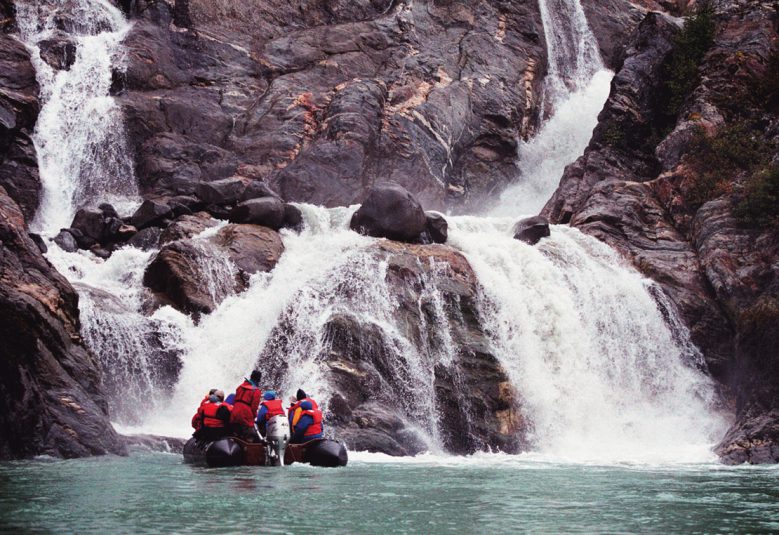 group in boat looking at waterfall in Alaska