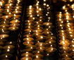 Many beautiful lit candles in a row glowing with a golden yellow light