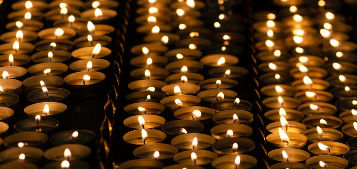 Many beautiful lit candles in a row glowing with a golden yellow light