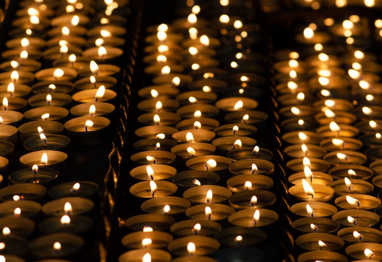 Many beautiful lit candles in a row glowing with a golden yellow light