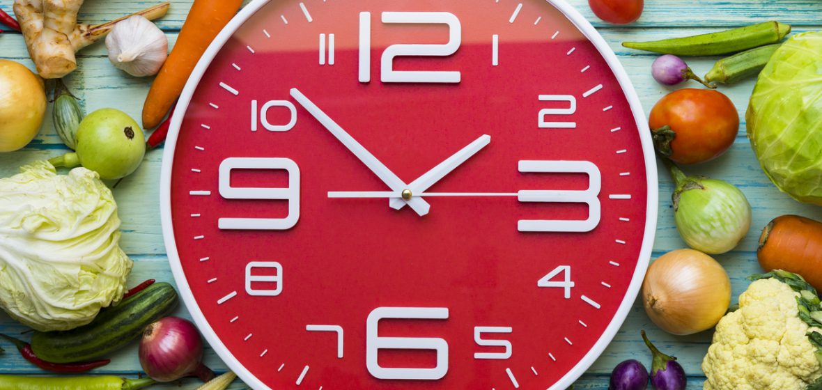 A clock surrounded by vegetables