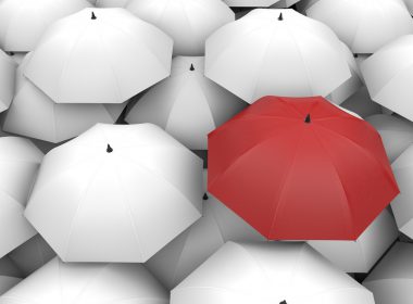 Red umbrella surrounded by white umbrellas