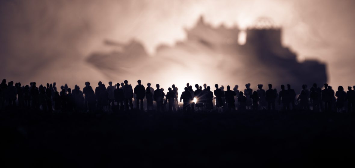 Silhouettes of a crowd standing at a border