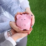 Two people holding a piggy bank