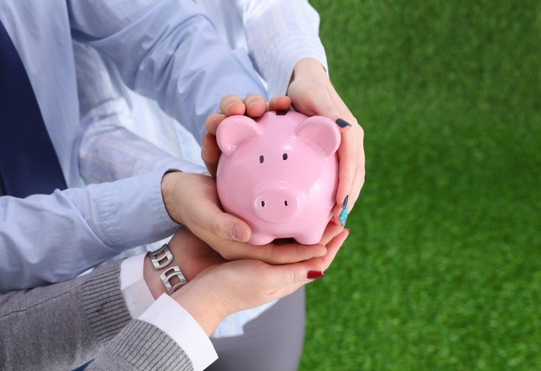 Two people holding a piggy bank