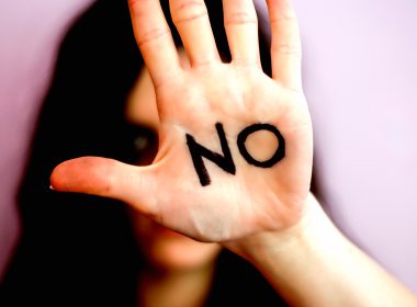 Woman holds a hand up with the word 'No' written on her palm
