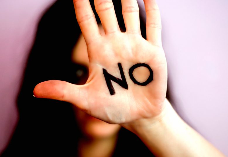 Woman holds a hand up with the word 'No' written on her palm