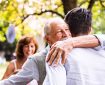 Older man hugs adult son at a party