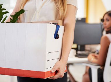 Woman carries a box of personal belongings from her desk