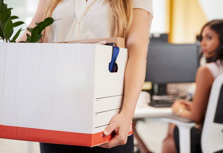 Woman carries a box of personal belongings from her desk