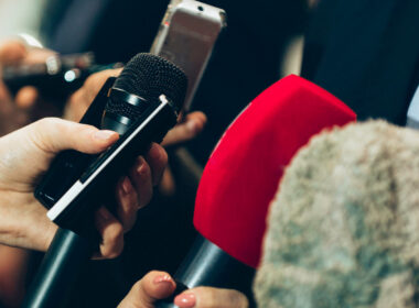 photo of hands reaching out with a microphone to portray how to work with media