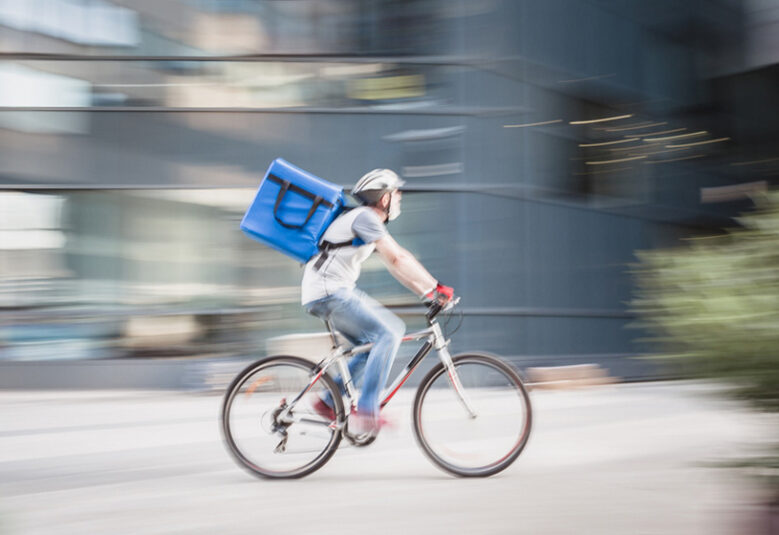 photo of cyclist with parcel speeding to show dangers of gig economy