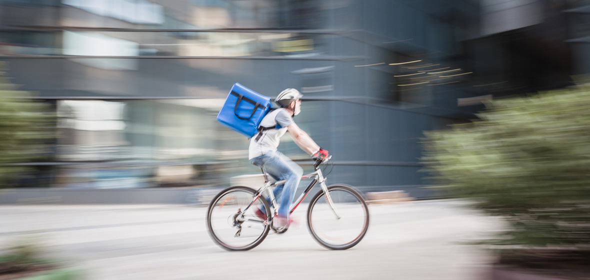 photo of cyclist with parcel speeding to show dangers of gig economy