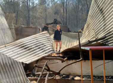 [image] photo of bushfire survivor with burned house