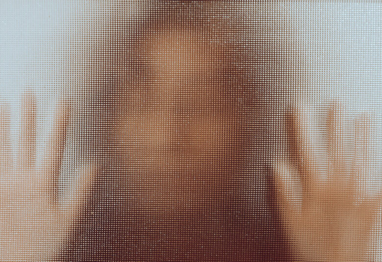 photo showing woman behind mottled glass with hands up