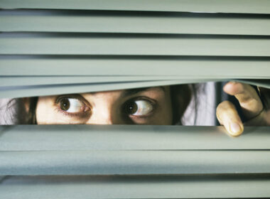 photo of woman peering through blinds