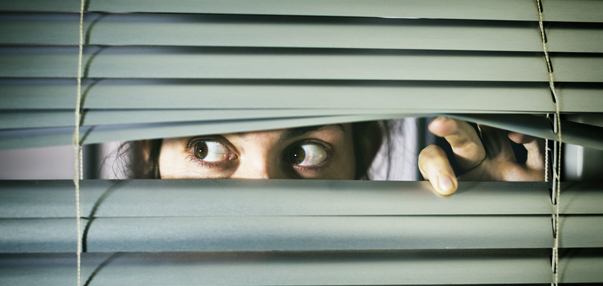photo of woman peering through blinds